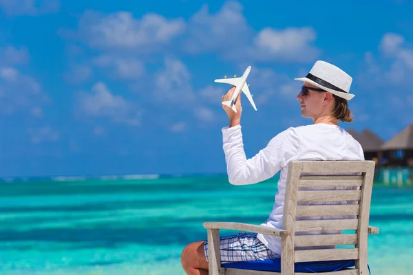 Young man with miniature of an airplane at tropical beach — Stock Photo, Image