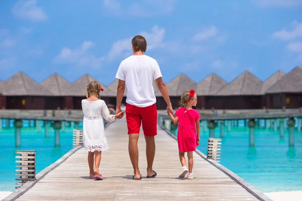 Little girls with dad on wooden jetty near water bungalow at exotic resort — Stock Photo, Image