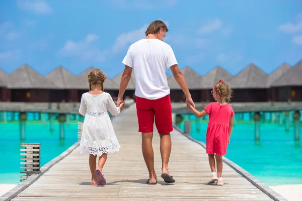 Meninas com o pai em molhe de madeira perto de bangalô de água no resort exótico — Fotografia de Stock