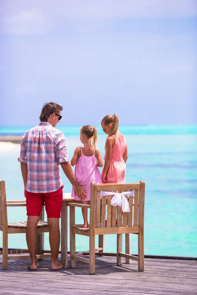 Glücklicher Vater und seine entzückenden kleinen Töchter am tropischen Strand — Stockfoto