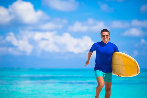Buon giovane surfista che corre in spiaggia con una tavola da surf — Foto Stock