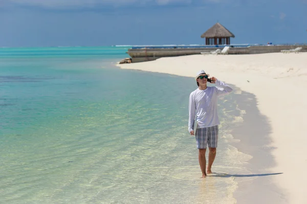 Hombre joven hablando por teléfono celular en la playa tropical — Foto de Stock