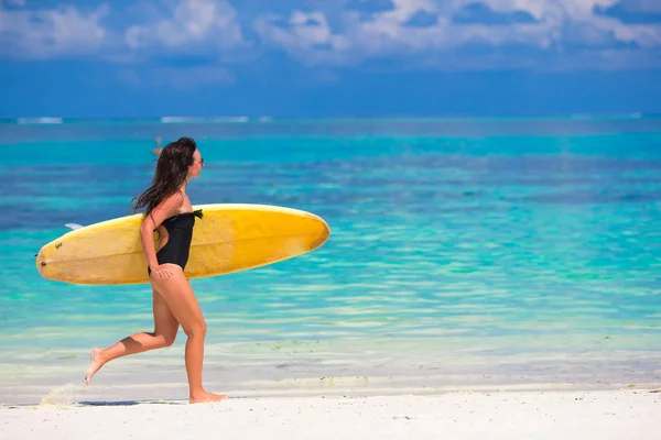 Feliz jovem surfista correndo na praia com uma prancha de surf — Fotografia de Stock