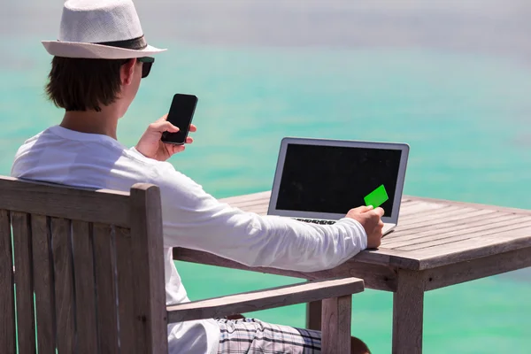 Jovem com tablet e celular na praia tropical — Fotografia de Stock