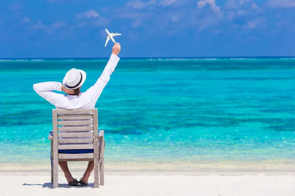 Young man with miniature of an airplane at tropical beach — Stock Photo, Image