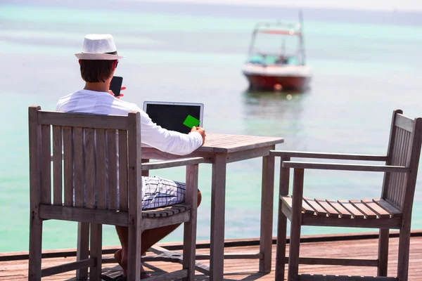 Anak muda dengan komputer tablet dan ponsel di pantai tropis — Stok Foto