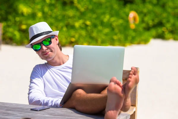 Молодой человек с планшетным компьютером во время отдыха на пляже — стоковое фото