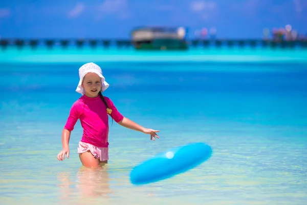 Kleines Mädchen spielt mit fliegender Scheibe am weißen Strand — Stockfoto