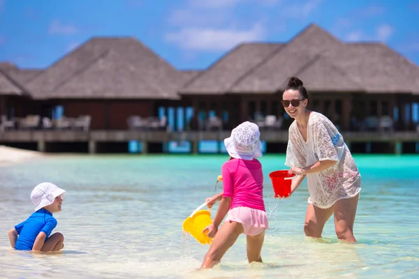 Очаровательные маленькие девочки и счастливая мама играют с пляжными игрушками на летних каникулах — стоковое фото
