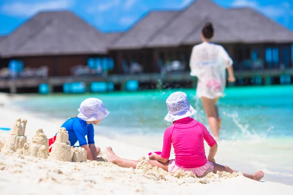 Due bambine e madre felice che giocano con i giocattoli sulla spiaggia in vacanza estiva — Foto Stock