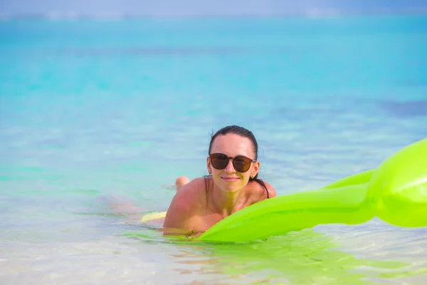 Jovem mulher feliz relaxando com colchão de ar na praia — Fotografia de Stock