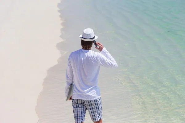 Young man talking by cell phone on tropical beach — Stock Photo, Image