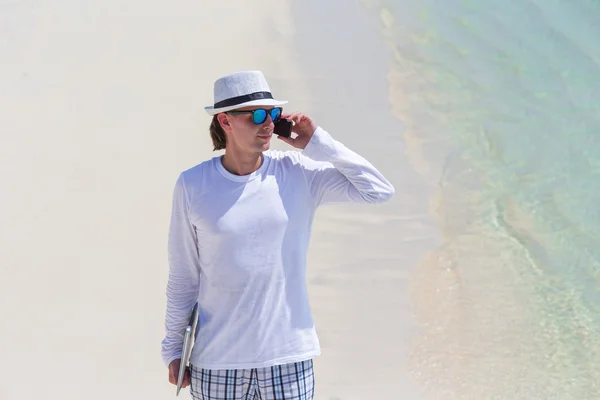 Hombre joven hablando por teléfono celular en la playa tropical — Foto de Stock
