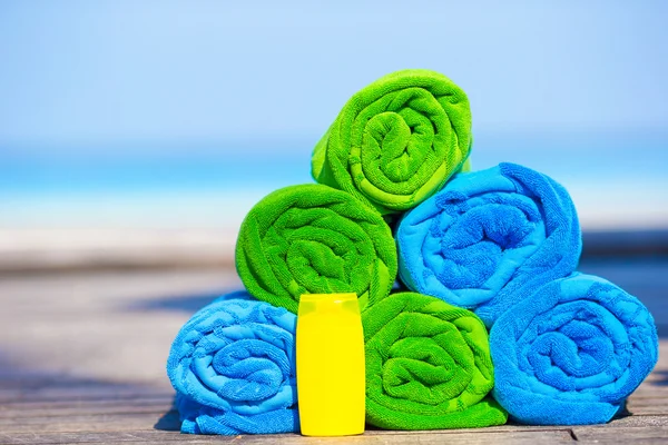 Nahaufnahme von bunten Handtüchern und Sonnencreme Flasche Hintergrund das Meer — Stockfoto