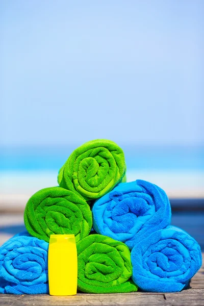 Close up of colorful towels and sunscreen bottle background the sea — Stock Photo, Image