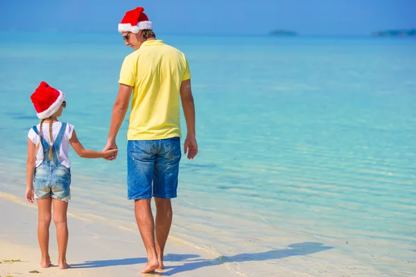 Kleines Mädchen und glücklicher Papa mit Weihnachtsmütze im Strandurlaub — Stockfoto