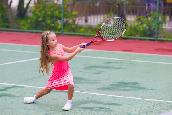Маленькая девочка играет в теннис на корте — стоковое фото