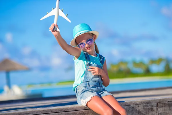 快乐的小女孩，手里拿着玩具飞机在白色沙滩上 — 图库照片
