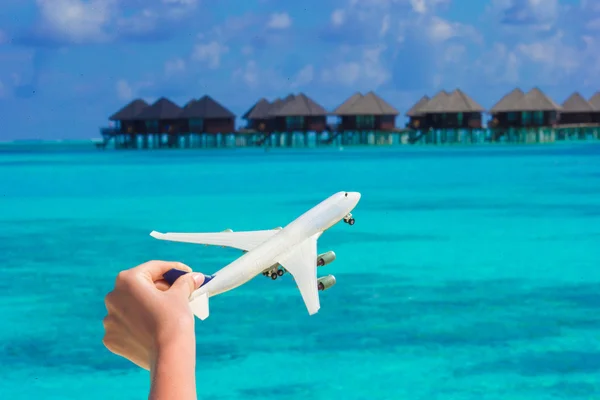 Piccolo aeroplano giocattolo bianco sulla spiaggia tropicale sfondo acqua bungalow — Foto Stock