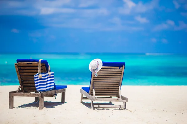 Lounge chairs with bag and hat on tropical white beach — Stock Photo, Image