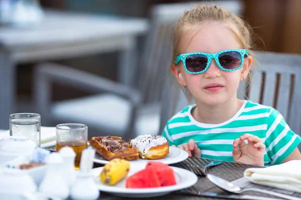 Очаровательная девочка завтракает в кафе на открытом воздухе — стоковое фото