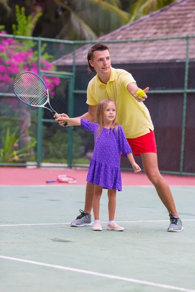 Niña jugando al tenis con su padre en la cancha —  Fotos de Stock