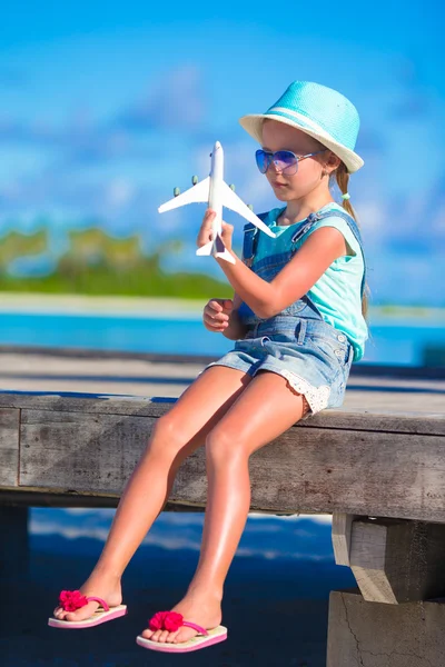Menina feliz com brinquedo avião em mãos na praia de areia branca — Fotografia de Stock