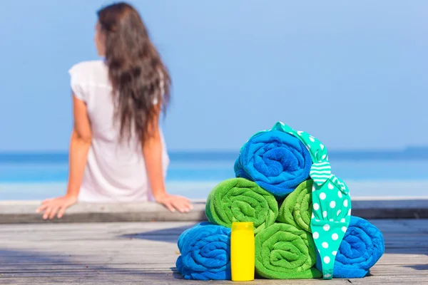 Spiaggia e accessori estate concetto asciugamani colorati, costume da bagno e crema solare sfondo bella donna — Foto Stock