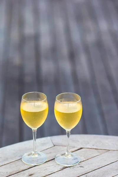 Two glasses of tasty white wine at sunset on wooden table — Stock Photo, Image