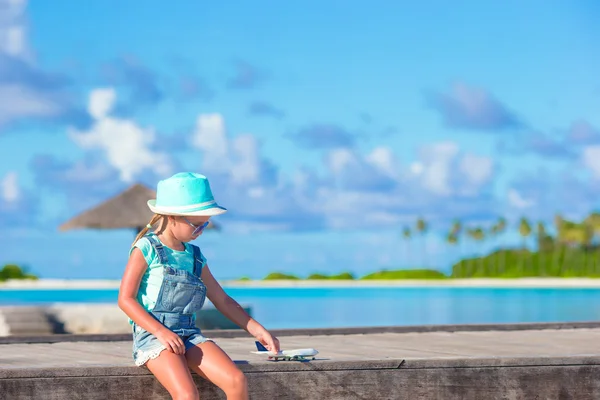 Lycklig liten flicka med leksak flygplan i händerna på vit sandstrand — Stockfoto