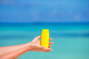 Suncream şişe arka plan mavi deniz ile eller