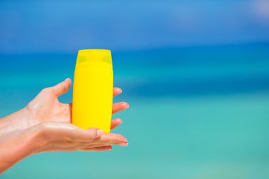 Suncream şişe arka plan mavi deniz ile eller