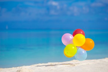 Beyaz tropik sahilde çok renkli balonlar