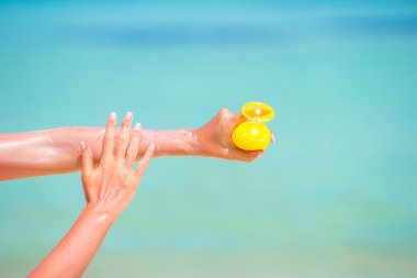 Suncream şişe arka plan mavi deniz ile eller