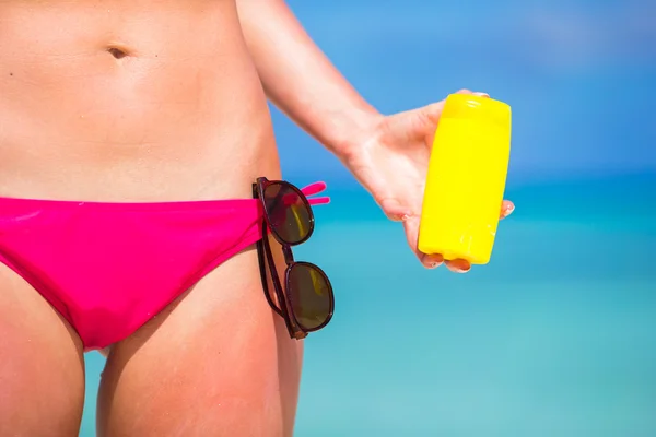 Genç kadın beyaz plajda güneş koruyucu ile uygulama — Stok fotoğraf