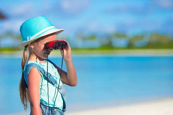 Little girl looking through binoculars in sunny day during summer vacation — Stock Photo, Image