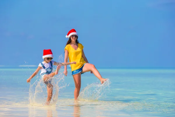 Lilla flickan och ung mamma i Santa hatt under strandsemester — Stockfoto
