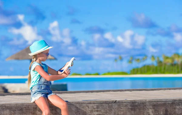 Happy little girl with toy airplane in hands on white sandy beach — Stock Photo, Image