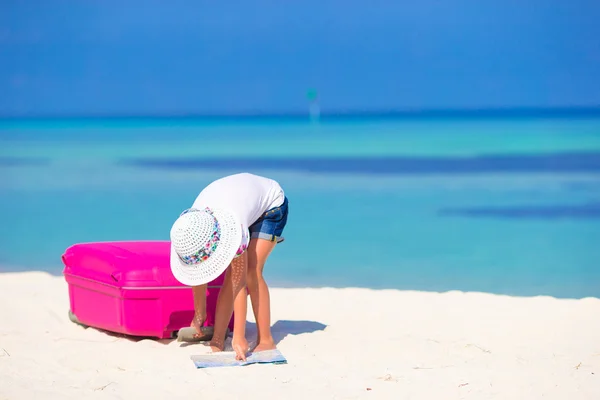 Little adorable girl with big suitcase on tropical white beach — Stock Photo, Image