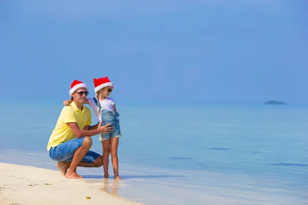 Little girl and happy dad in Santa Hat during beach vacation — Stock Photo, Image