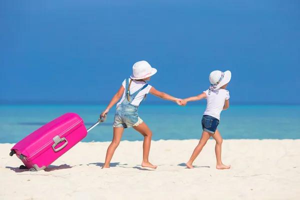 Weinig toeristen meisjes met grote koffer op tropische witte strand — Stockfoto