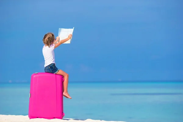 Piccola adorabile ragazza con grande valigia rosa e mappa dell'isola sulla spiaggia bianca — Foto Stock