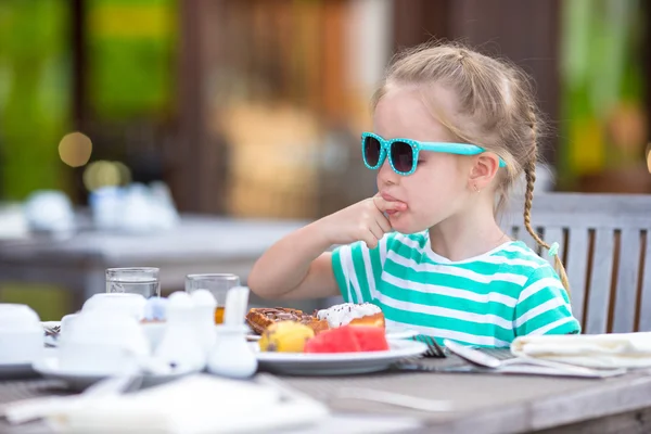 Adorable niña tomando el desayuno en la cafetería al aire libre —  Fotos de Stock