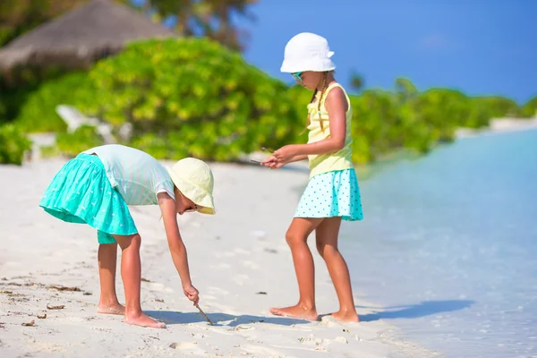 Little adorable girls drawing picture on white beach — Stock Photo, Image
