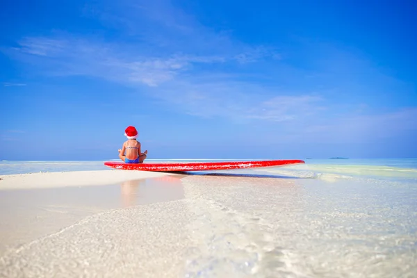 Entzückendes kleines Mädchen mit Weihnachtsmütze am Strand im Urlaub — Stockfoto