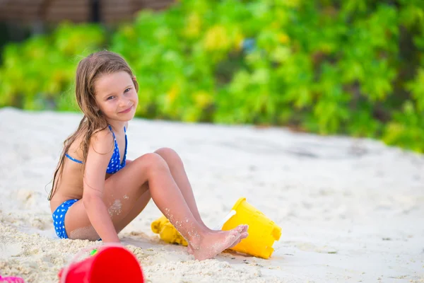 Adorable little girl playing with beach toys during tropical vacation — Stock Photo, Image