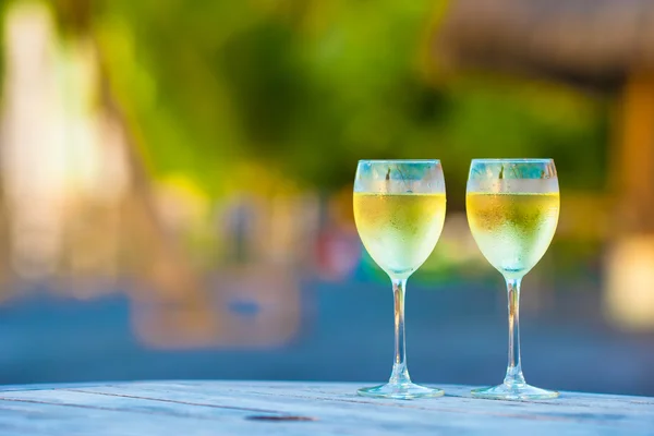 Deux verres de vin blanc savoureux au coucher du soleil sur une table en bois — Photo