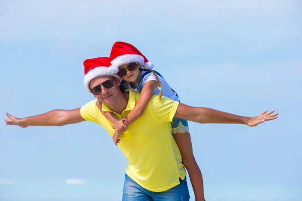 Küçük kız ve beach tatil sırasında Noel Baba şapkası içinde mutlu baba — Stok fotoğraf