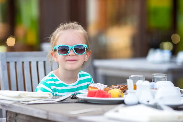 Liebenswertes kleines Mädchen frühstückt im Café im Freien — Stockfoto