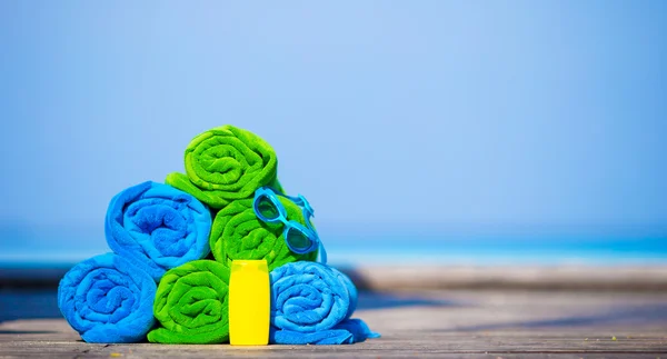 Beach and summer vacation accessories concept - close-up of colorful towels, swimming goggles and sunblock — Stock Photo, Image